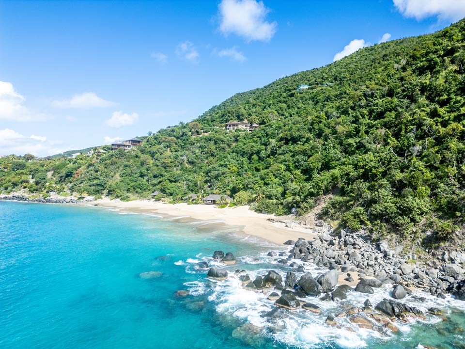 Aerial view of the north shore of Virgin Gorda, showing the villa set into a wooded hillside above a curved sand beach