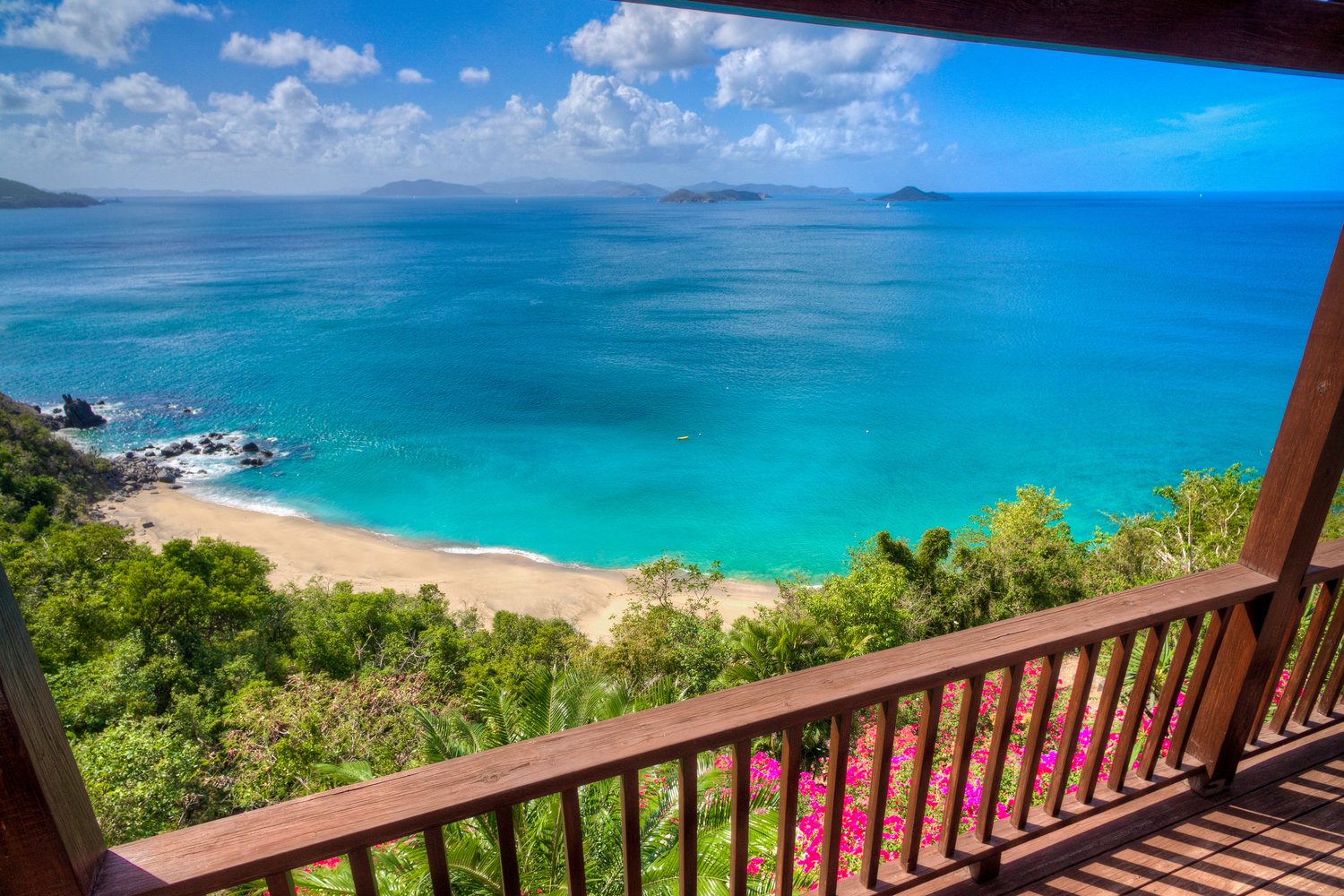 View from the villa's balcony down over a sandy cove and turquoise water