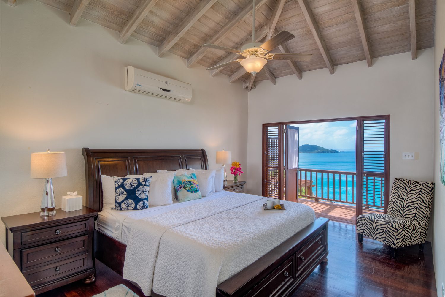 Fourth bedroom with a dark wood sleigh bed, white linens and a private balcony over the water