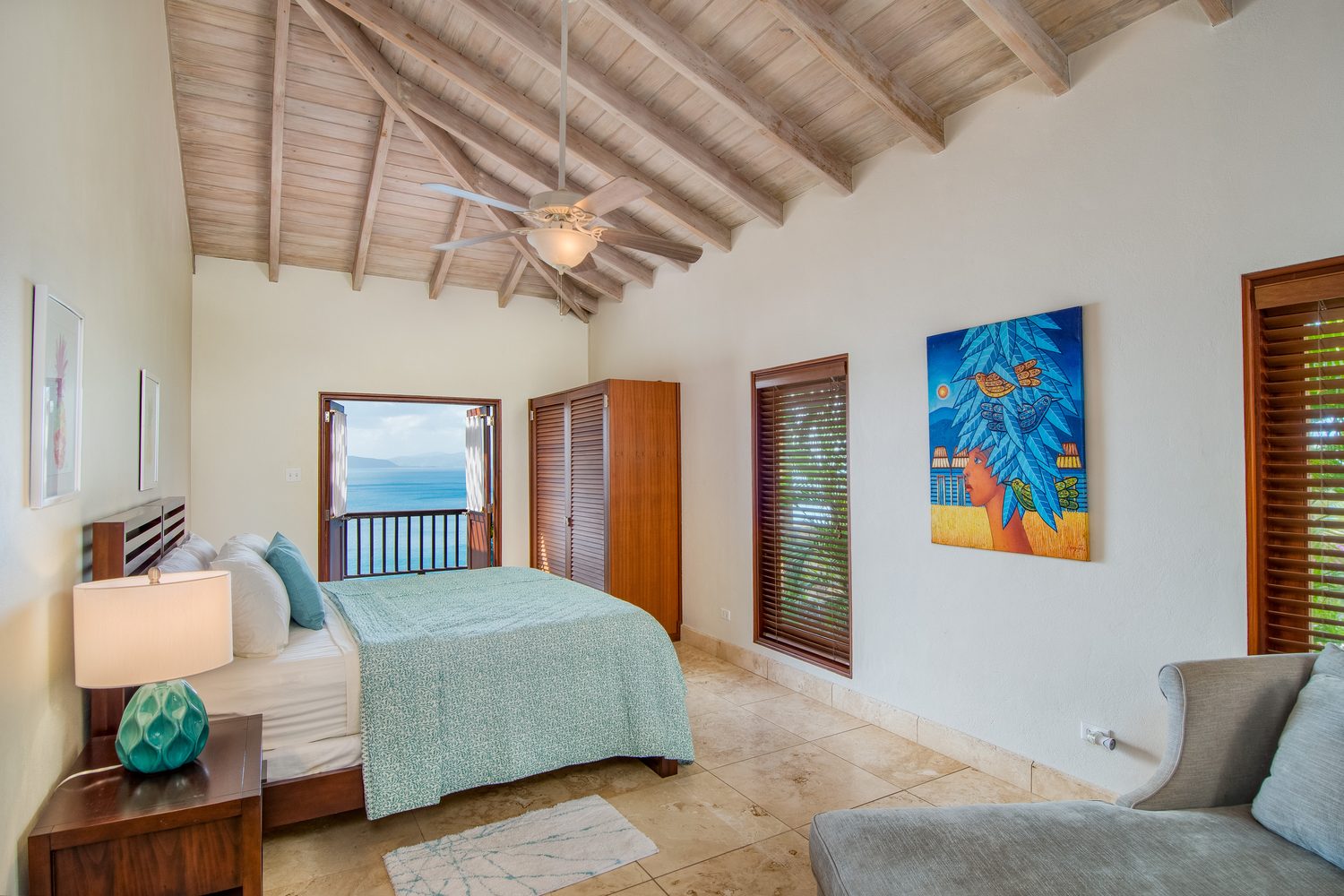 Third bedroom with vaulted wood ceiling, seafoam linens and a private balcony over the water