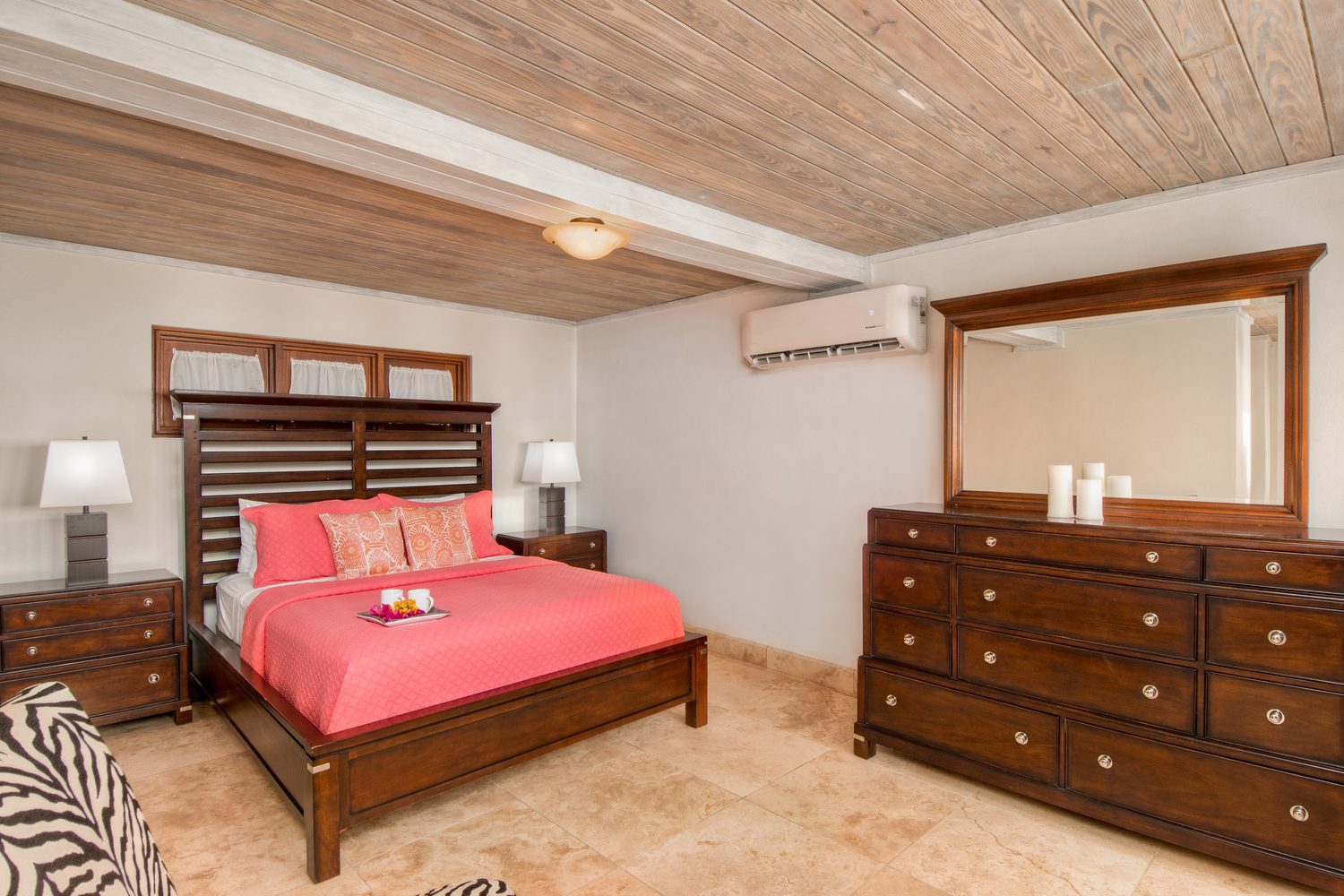 Second bedroom with a dark wood bed, coral linens and a wood-plank ceiling