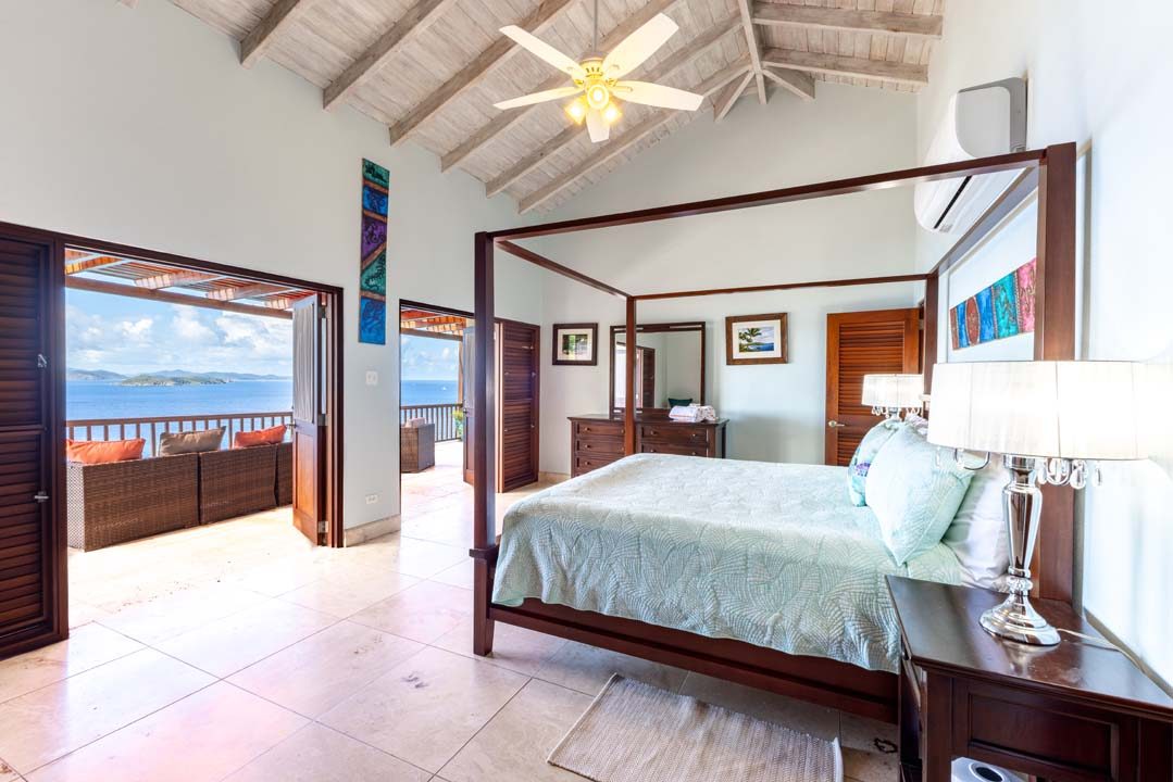 Primary bedroom with a mahogany four-poster bed, vaulted ceiling and ocean view