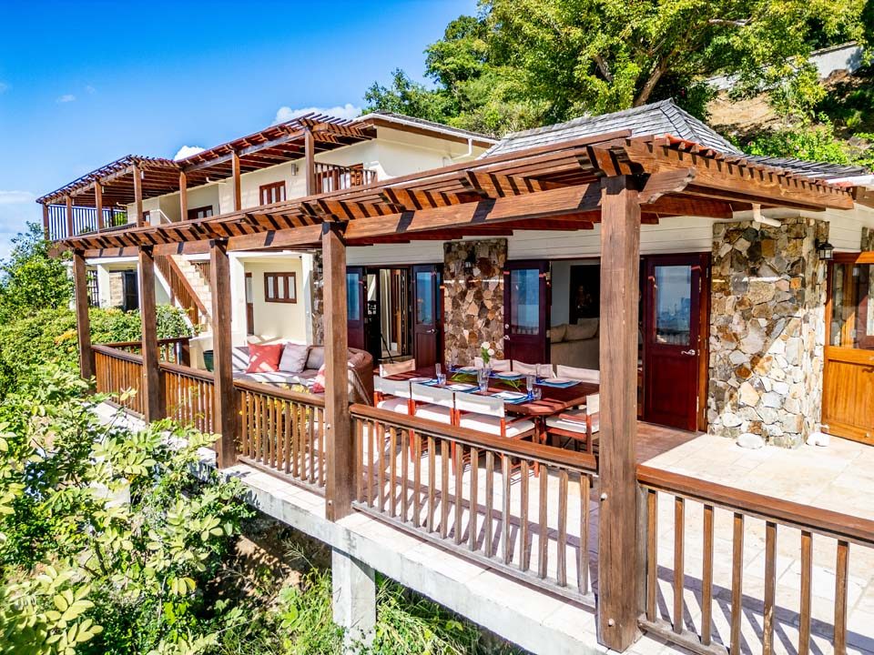 Exterior of Turtle Bay House, with stone walls, mahogany doors and a wooden pergola